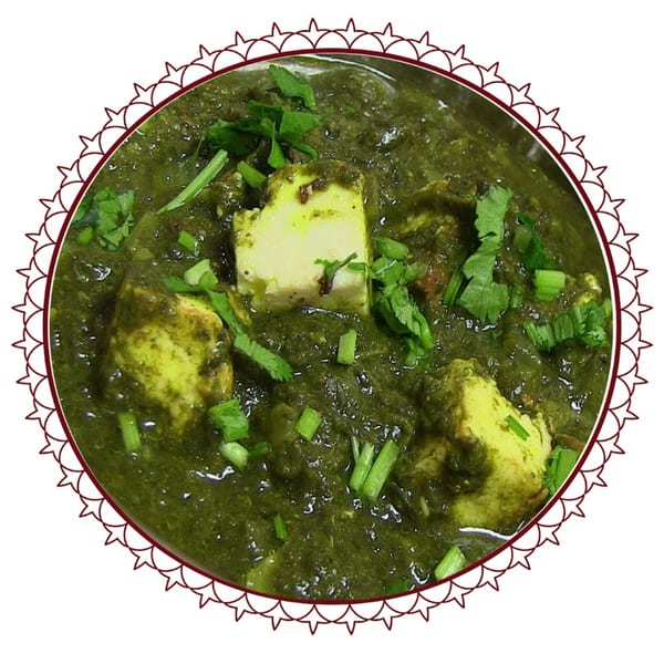 Close-up of vibrant green Palak Paneer curry with paneer cubes and fresh herbs.
