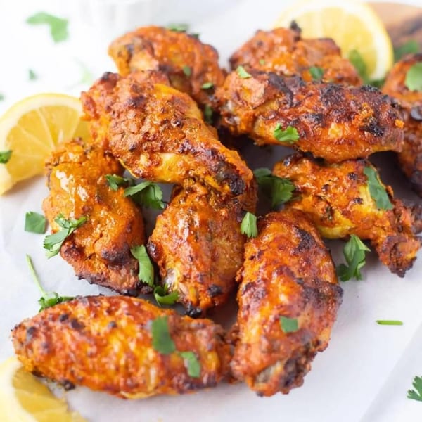 Tikka Curry & Grill's chicken wings, garnished with cilantro and lemon wedges.
